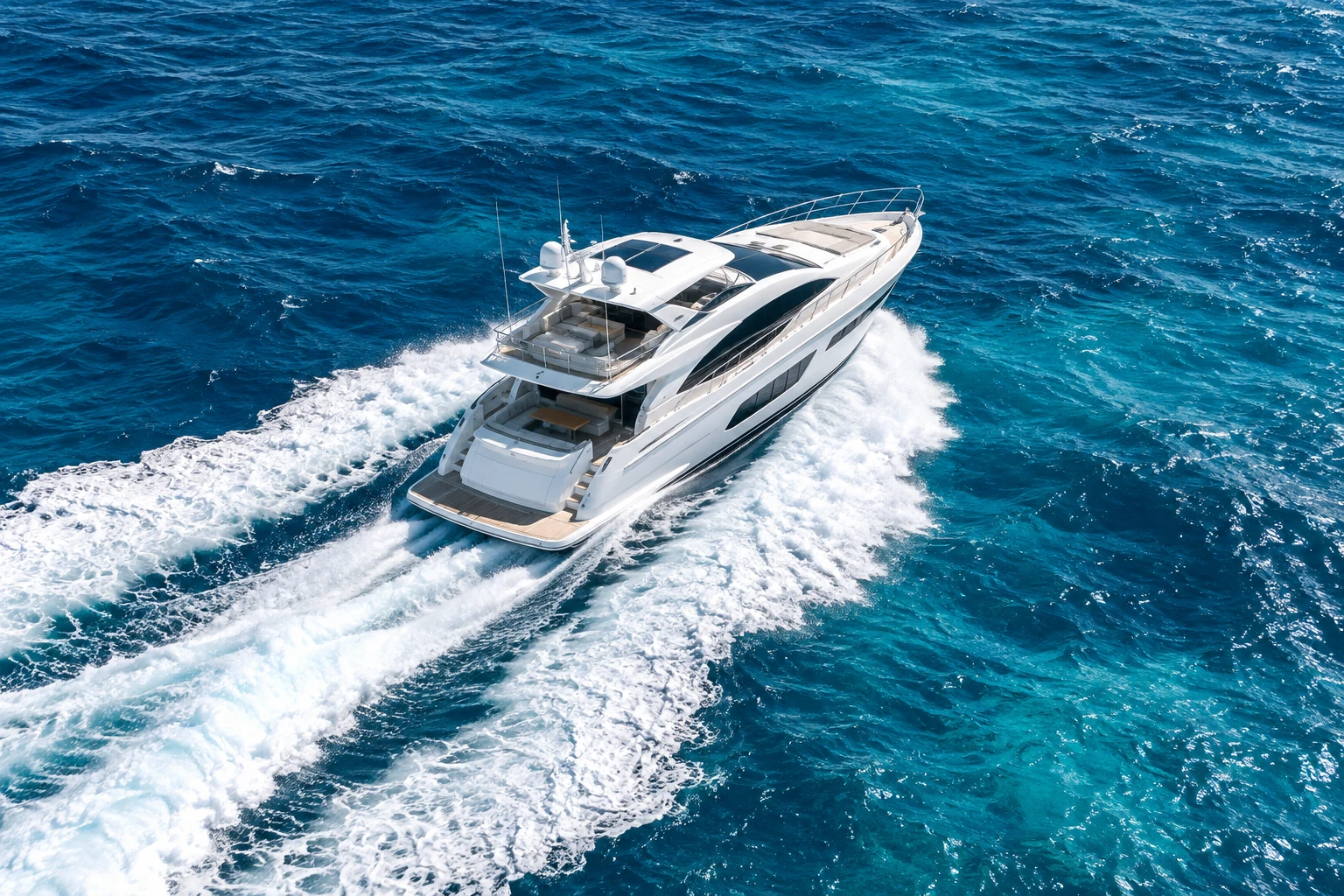 A white motor yacht underway through vivid blue open water